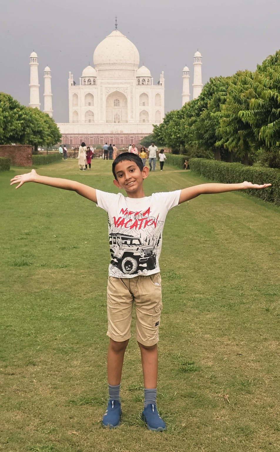Dripto with arms outstretched in front of the Taj Mahal.